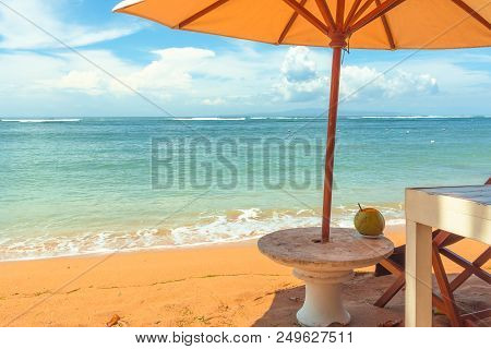 A Chair And A Stone Table On The Yellow Beach Under A Parasol, Relaxing With A Coconut-drink. Sanur,