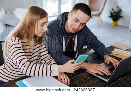 Look Here. Serious Blond Girl Sitting Near Her Boyfriend And Showing Photos On Her Phone