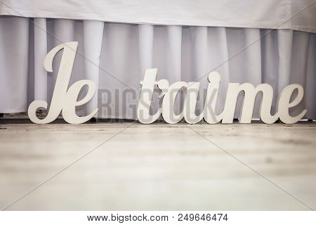 Volumetric White French Words Je Taime On A Wedding Party. Decorations Made From Wood Standing On Th