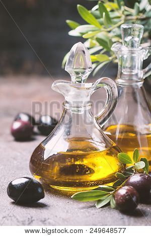 Olive Oil In A Glass Bottle And Olive Branch On Brown Stone Table