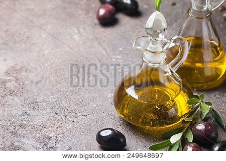 Olive Oil In A Glass Bottle And Olive Branch On Brown Stone Table