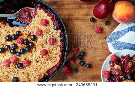 Food Background. Crumble With Blueberries In The Black Cast-iron Frying Pan On The Wooden Cutting Bo