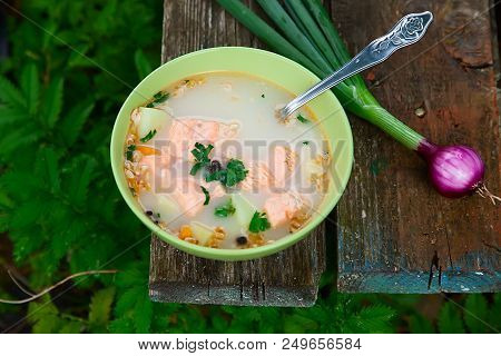 Fish Soup On An Old Wooden Table In Nature Among The Green Grass