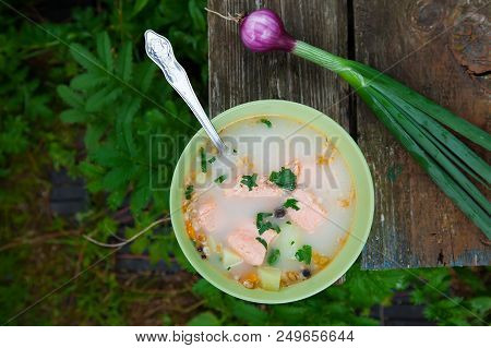 Fish Soup On An Old Wooden Table In Nature Among The Green Grass