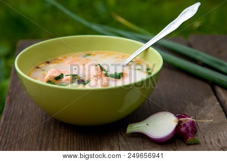 Fish Soup On An Old Wooden Table In Nature And Red Onions With Pine Nuts