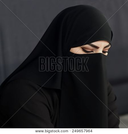 Portrait Of An Arabic Young Woman From Qatar In Traditional Islamic Cloth Niqab Against On Dark Back