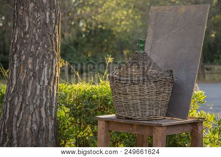 Image Of A Large Wicker Carboy Placed Over A Wooden Table