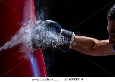 Close-up Hand Of Boxer At The Moment Of Impact On Punching Bag Over Black Background. Strength And M