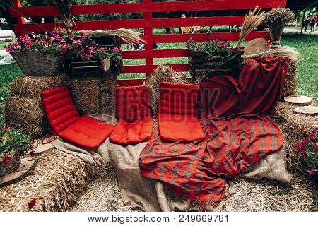 Rustic Photo Booth. Rural Photo Zone With Haycocks, Hay Chairs And Flowers Arrangement At Wedding Re