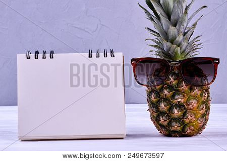 Pineapple In Sungasses And Blank Paper Notepad. Whole Green Ananas And Empty Paper Notebook. Plannin