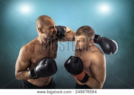 Two professional boxers, athletes in dynamic boxing action on the ring under lights of sport arena.