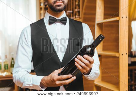 Cropped Shot Of Young Wine Steward With Bottle Of Luxury Wine At Wine Store
