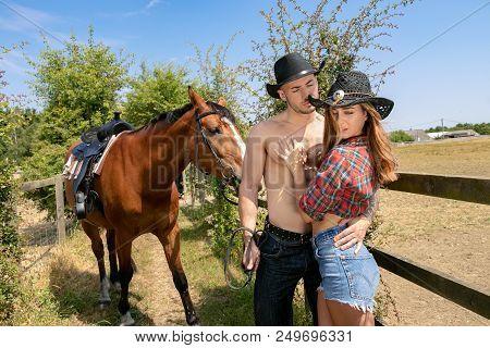Cowboy And Cowgirl Couple With Horse And Saddle Argue With Ranch In Background