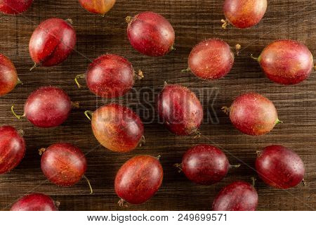 Lot Of Whole Fresh Red Gooseberry Hinnomaki Variety Flatlay On Brown Wood