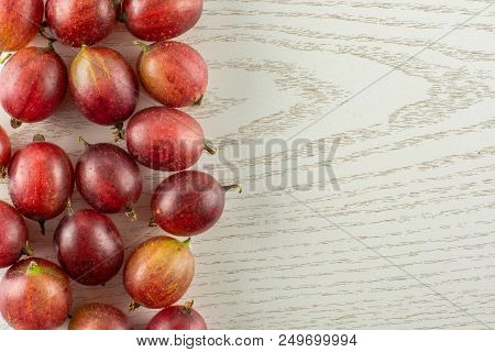 Lot Of Whole Fresh Red Gooseberry Hinnomaki Variety Left Corner Flatlay On Grey Wood