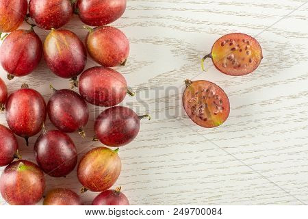 Lot Of Whole Fresh Red Gooseberry Hinnomaki Variety One Cut In Two Section Halves Flatlay On Grey Wo