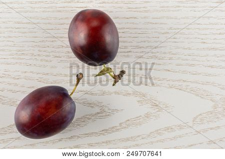 Group Of Two Whole Fresh Violet-blue Plum Vibrant Moyer Variety Flatlay On Grey Wood