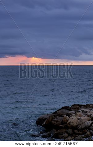 Puerto Vallarta Bay With A Dramatic Orange Sunset On The Horizon And Rocks In The Foreground.