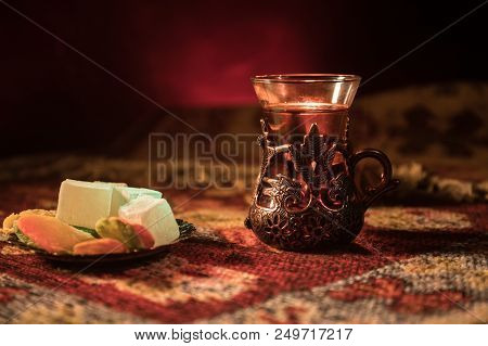 Arabian Tea In Glass With Eastern Snacks On A Carpet On Dark Background With Lights And Smoke. Easte