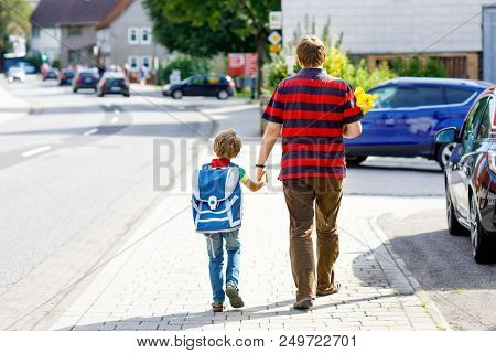 Parent Taking Child, Kid Boy To School. Pupil Of Primary School Go Study. Father Holding Hand Of Lit