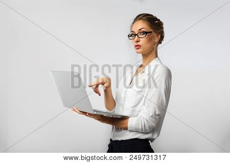 A Strict Business Lady In Glasses And Co-ordinate Office Clothes Is Holding A Laptop In Her Hands An