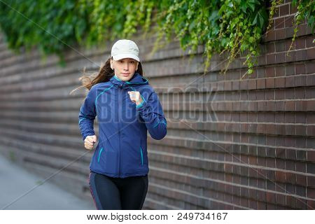 Young Woman Jogging Along The Street In Eurpean City In The Morning. Running Fitness Girl Against Br