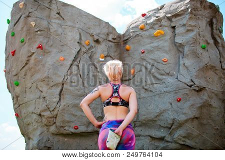 Photo from back of young woman climber with bag of soap against rock boulder