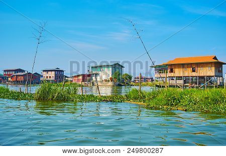 The Green Fence With Timber Poles Separates The Canal Of Inpawkhon Village From Main Water Source Of