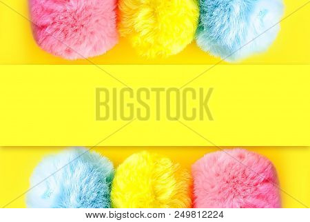 Colorful Fluffy Pompons On Bright Yellow Background. Fashion Decoration Festive Template. Design Ele