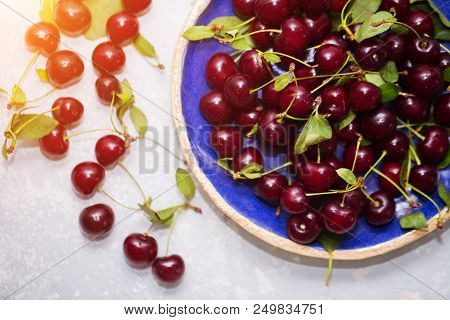Ripe Cherry In A Blue Plate On A Light Background