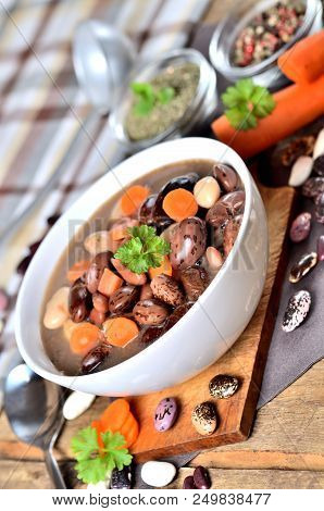 Bean Soup With Large Beans On Cutting Board, Carrots, Parsley, Marjoram, Spoon And Ladle - Vertical 