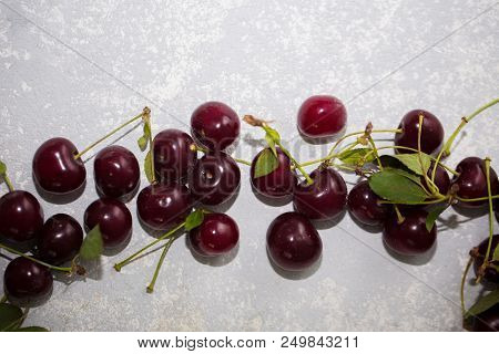 Fresh Ripe Cherries With Leaves On Grey Table