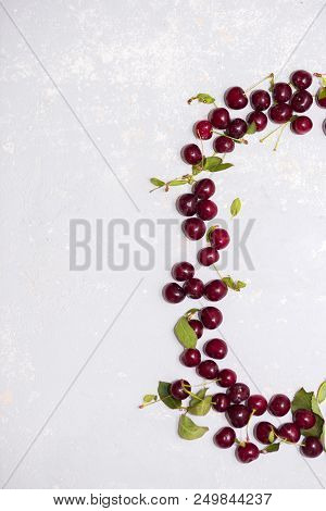 A Few Ripe Cherries On A Gray Textured Background, Top View