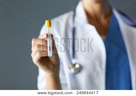 Female medical or research scientist or doctor using looking at a test tube of clear solution in a lab or laboratory.