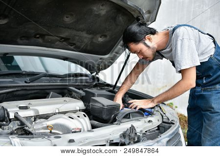 Car Repair Concept. Asian People Are Repairing Cars On The Roadside. Asian Guy Fixes Car With Confid