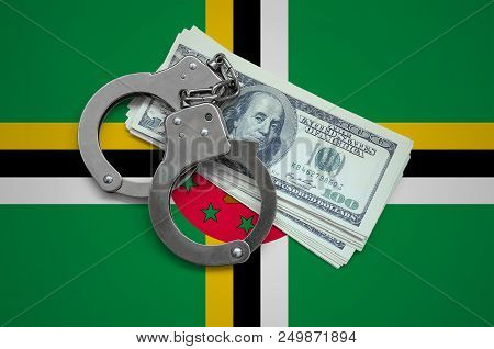 Dominica Flag  With Handcuffs And A Bundle Of Dollars. Currency Corruption In The Country. Financial