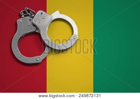 Guinea Flag  And Police Handcuffs. The Concept Of Crime And Offenses In The Country.