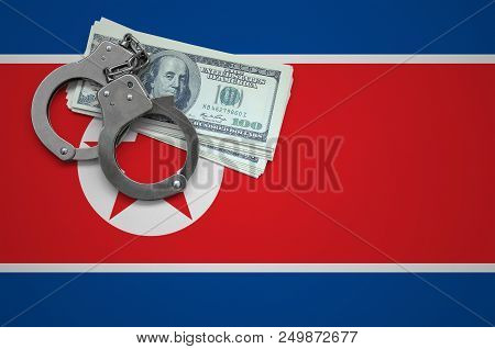 North Korea Flag  With Handcuffs And A Bundle Of Dollars. The Concept Of Breaking The Law And Thieve