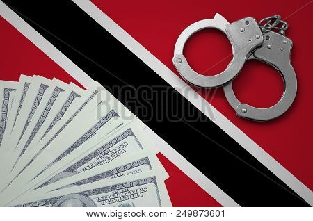 Trinidad And Tobago Flag  With Handcuffs And A Bundle Of Dollars. The Concept Of Illegal Banking Ope