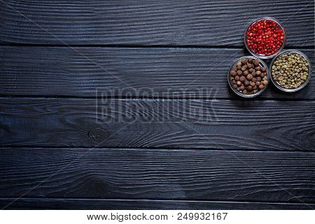 Assortment Of Different Kinds Of Pepper, Red, Green And Allspice On Rustic Wooden Black Background. 