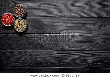 Assortment Of Different Kinds Of Pepper, Red, Green And Allspice On Rustic Wooden Black Background. 