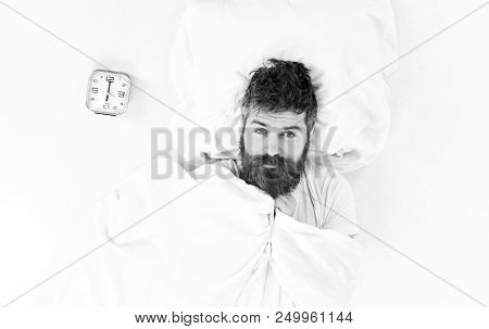 Morning Wake Up Concept. Man With Calm Face Lies On Pillow Near Alarm Clock. Man Already Awake, Need