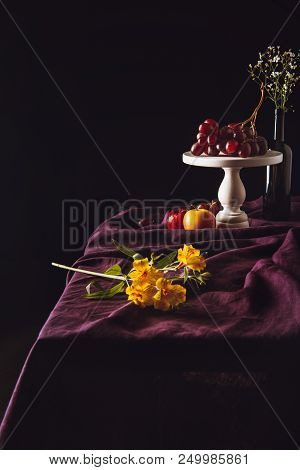 Beautiful Flowers Lying On Table With Fruits On Background