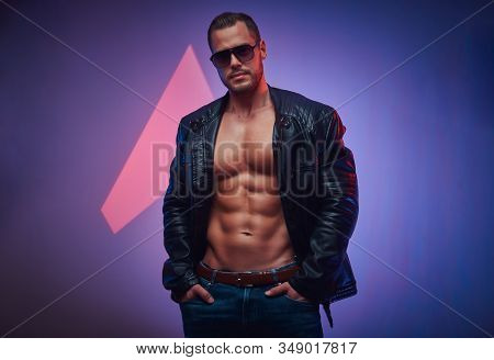 Sexy Man In Leather Jacket And Sunglasses Is Posing For Photographer At Photo Studio.