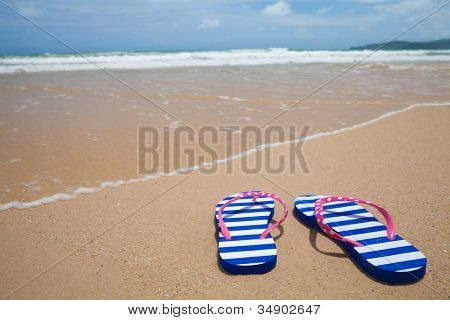 Barevné rozcajdaný obuvi na mořské pláži. Holiday koncept.