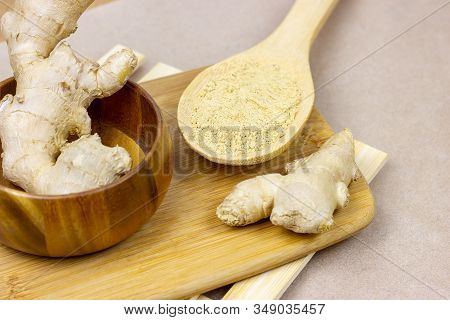 Fresh Raw Yellow Ginger Root With Ground Dry Powder In Wooden Spoon And On Wood Background.