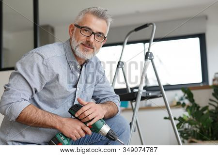 Man at home using electric drill, do-it-yourself work