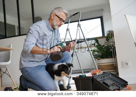 Man at home doing do-it-yourself work with puppy around