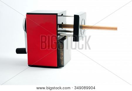 Rotary Pencil Sharpener. Red Black Rotary Pencil Sharpener With Brown Pencil On White Background.