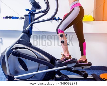 Young Sports Woman With Electrostimulator On The Muscles Of The Legs.